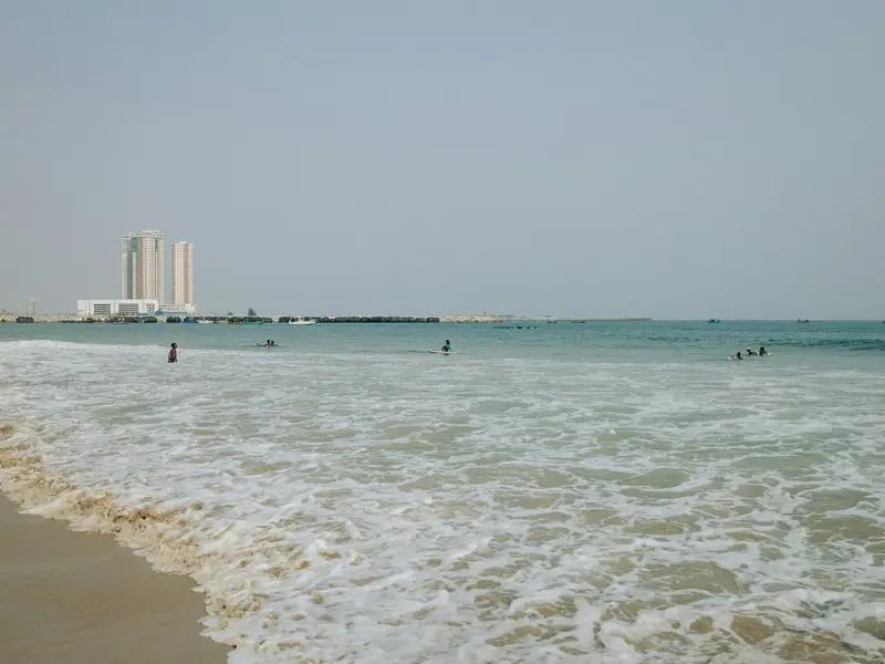 Swimmers and surfers at Tarkwa Bay, with Eko Atlantic towers across the water
